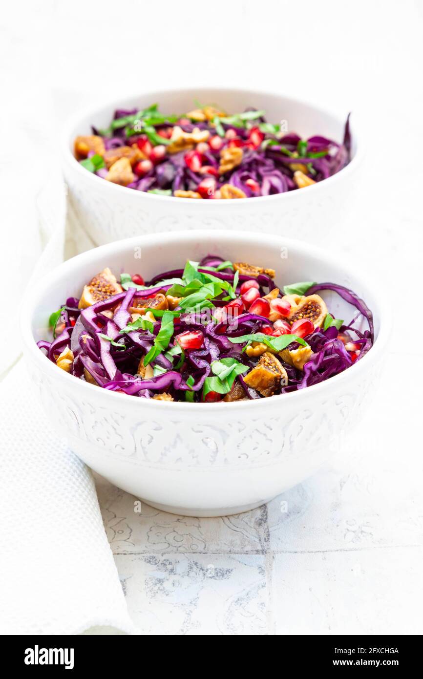 Due ciotole di insalata vegana con cavolo rosso, semi di melograno, fichi secchi, noci e basilico Foto Stock