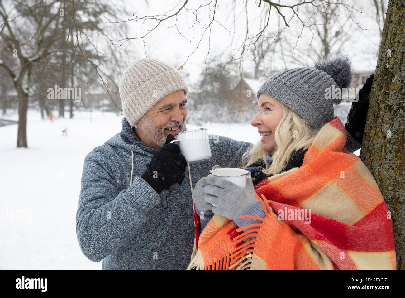 Una coppia sorridente che beve tè in tazza durante l'inverno Foto Stock
