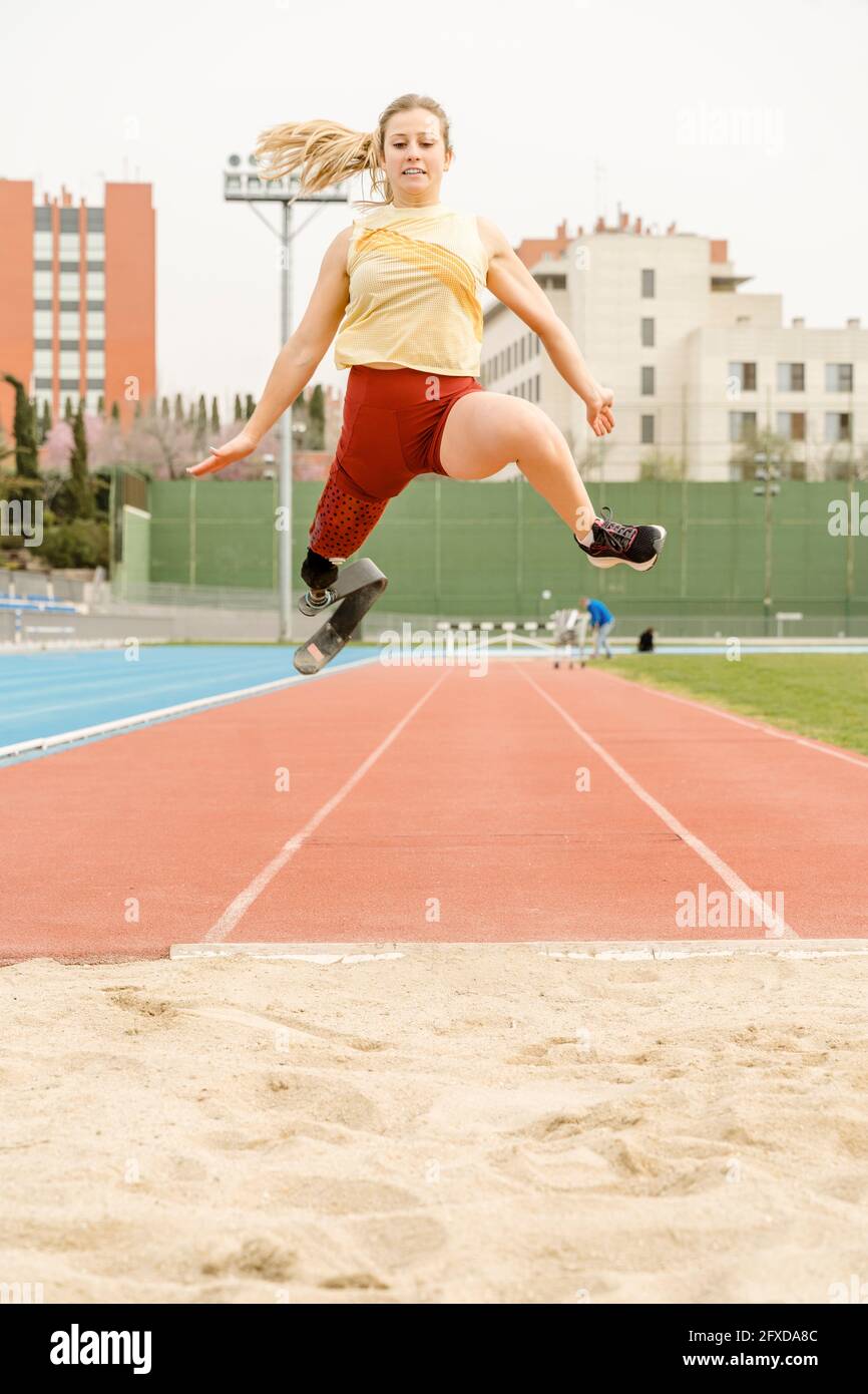 Sportiva per disabili che salta sulla sabbia durante l'allenamento Foto Stock