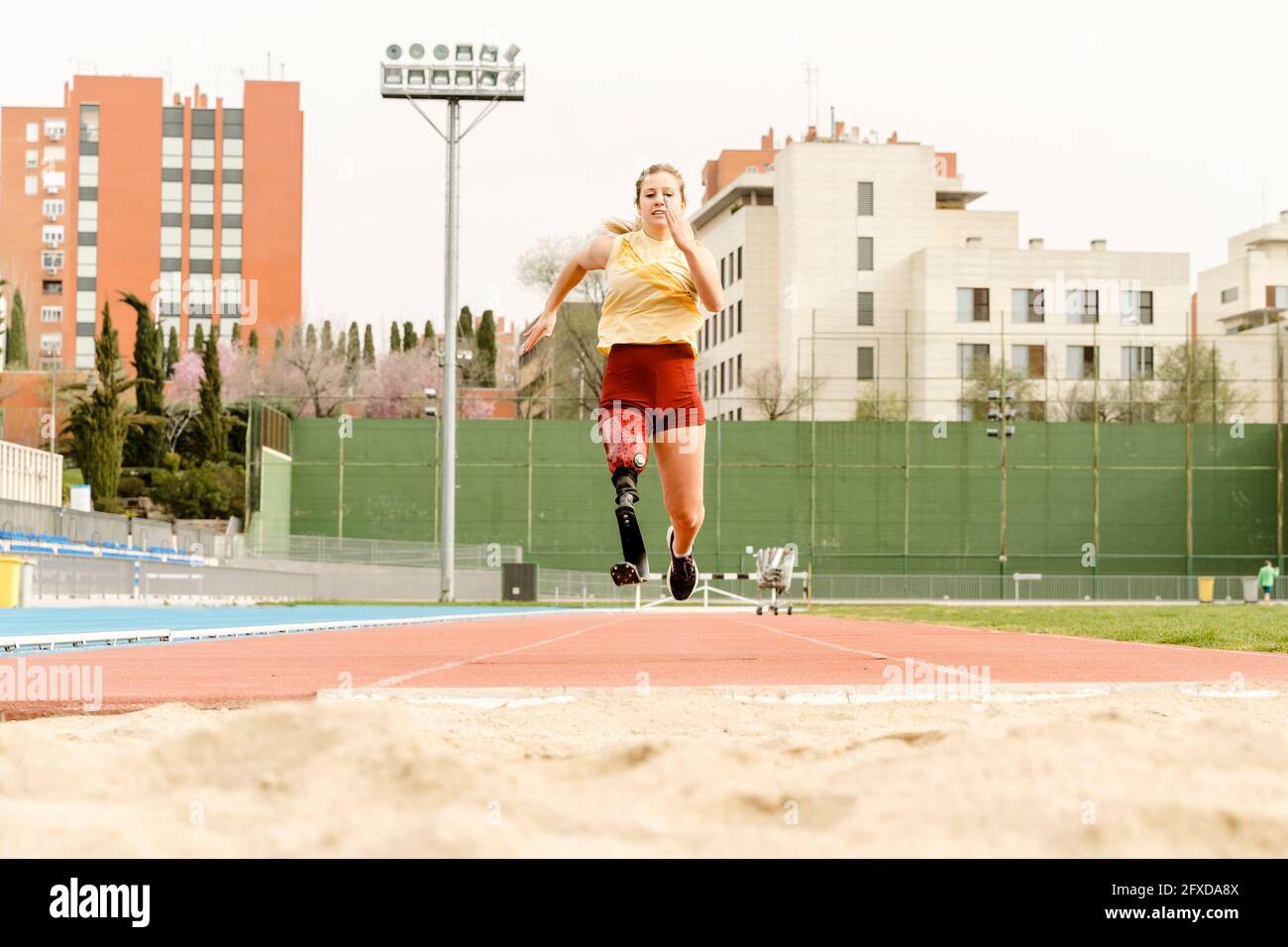 Atleta con disabilità che corre verso il sandpit Foto Stock