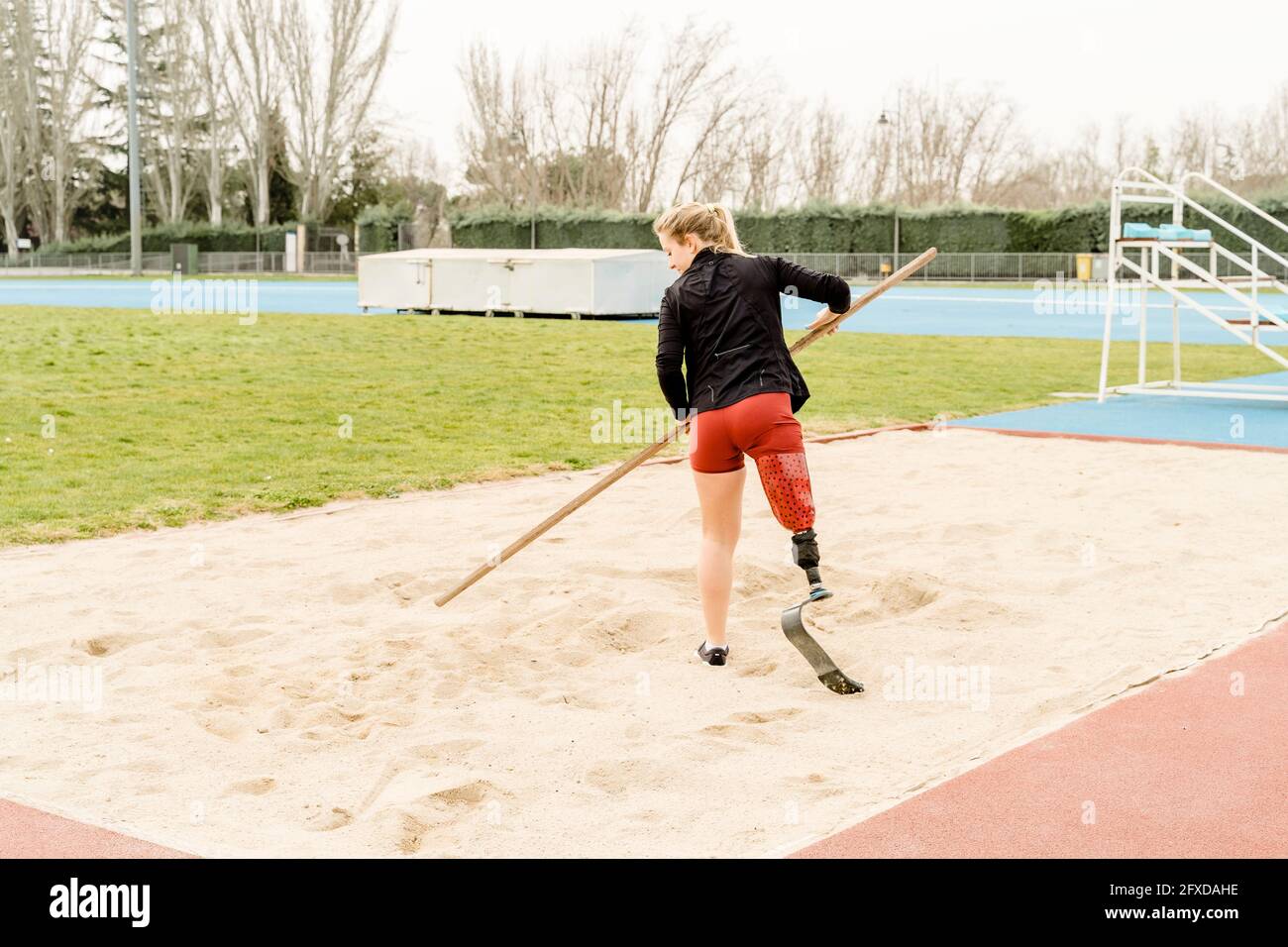 Sportiva per disabili che prepara la sabbia sullo stadio Foto Stock