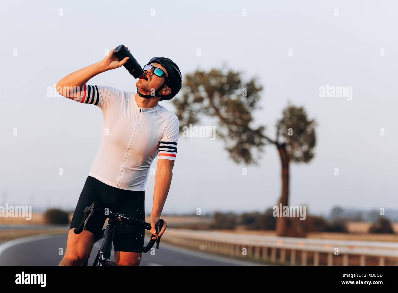 Forte ciclista rinfrescante con acqua dopo una lunga corsa Foto Stock