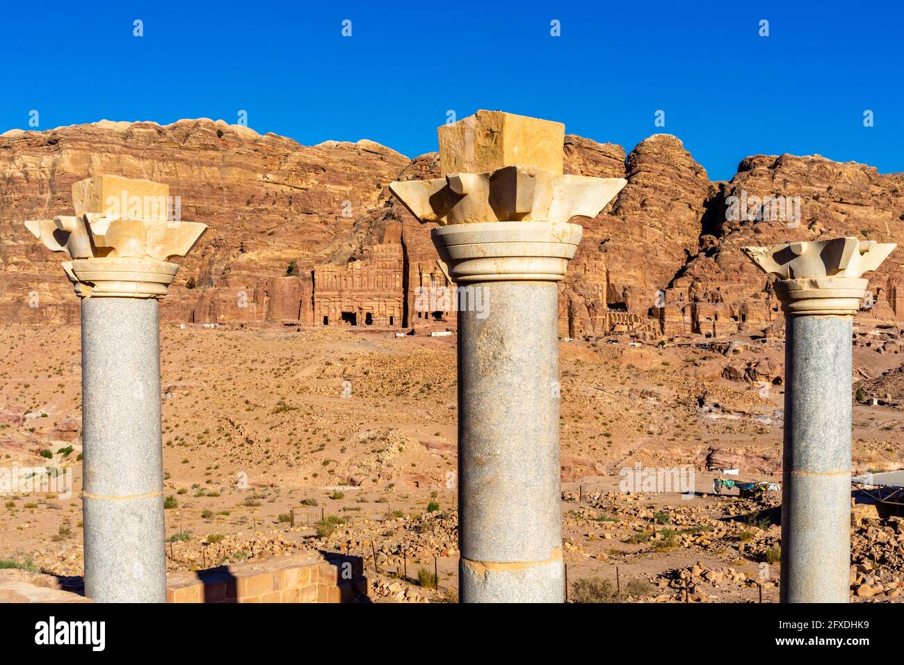 Tre colonne della Cappella Blu in granito blu egiziano, capitelli Nabataei cornuti, tombe sullo sfondo, Petra, Giordania Foto Stock