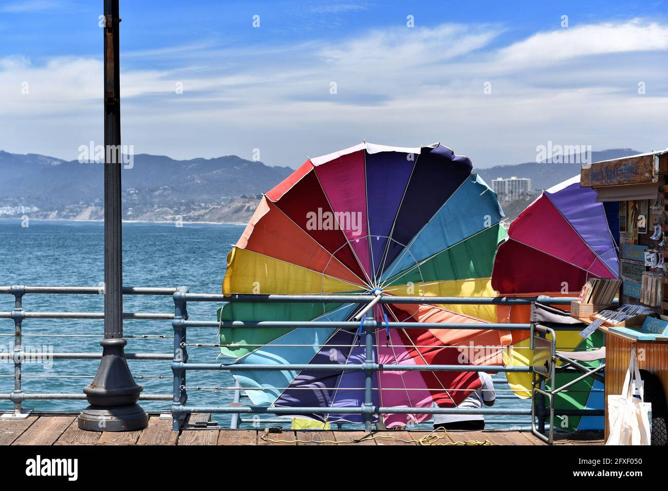 SANTA MONICA, CALIFORNIA - 25 MAGGIO 2021: Ombrelli colorati sul molo con le montagne di Santa Monica e la baia sullo sfondo. Foto Stock