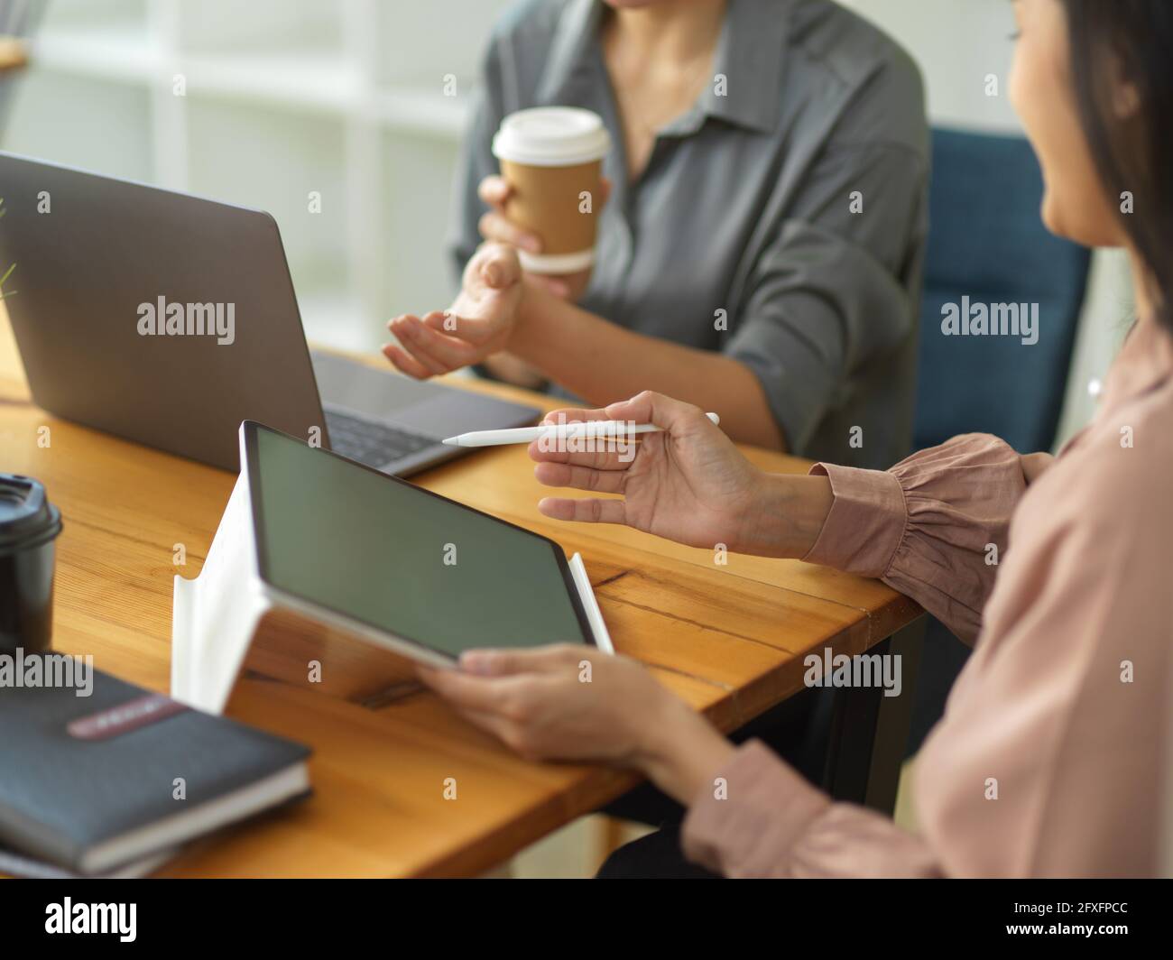 Vista ravvicinata di due donne d'affari che utilizzano il tablet digitale e. computer portatile durante la condivisione delle idee nella sala riunioni Foto Stock