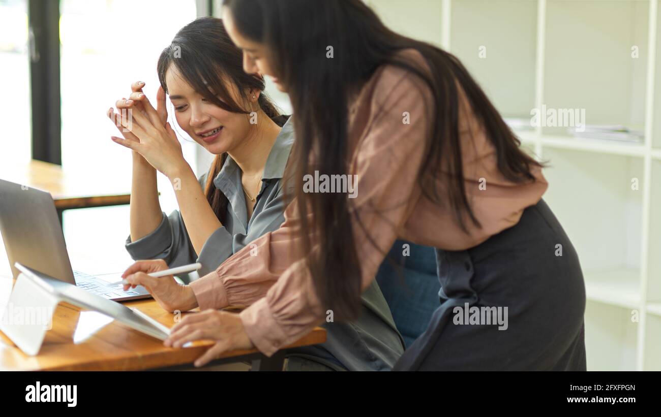 Ritratti di due donne d'affari che condividono idea l'una all'altra mentre lavorare insieme in ufficio Foto Stock