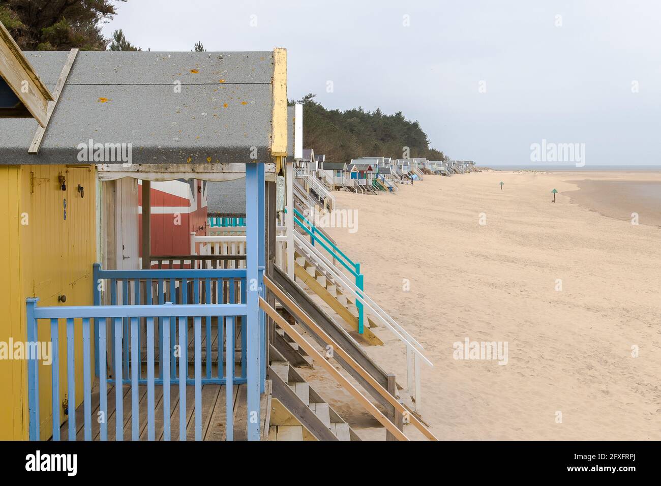 Una lunga linea di capanne si estende lungo il fronte mare a Wells-Next-Sea a Norfolk. Foto Stock