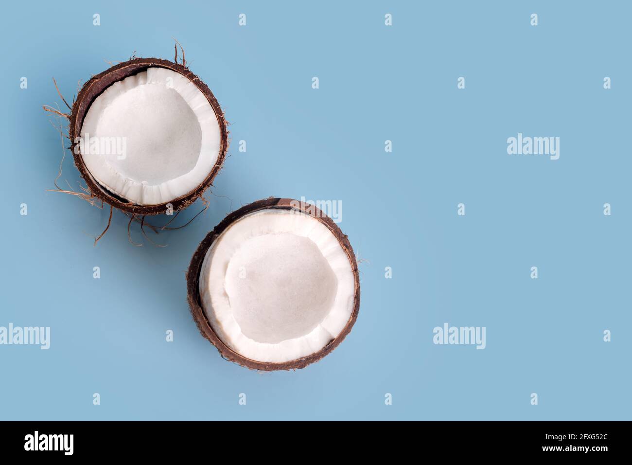 Spaccato a metà cocco su sfondo azzurro. Noce di cocco fresco tagliato a metà. Foto Stock