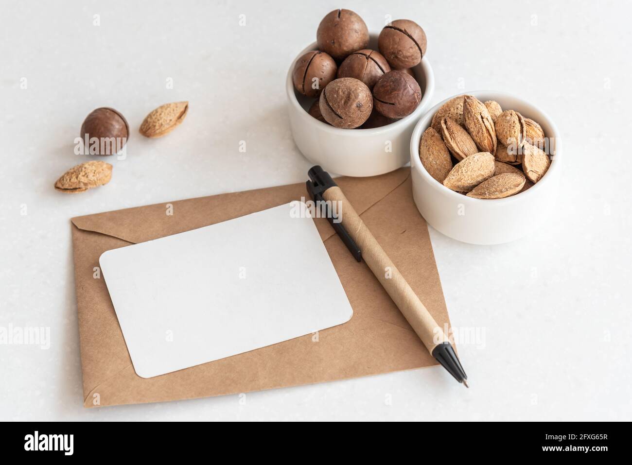 Biglietto da visita e penna sulla busta con noci esotiche tabella Foto Stock
