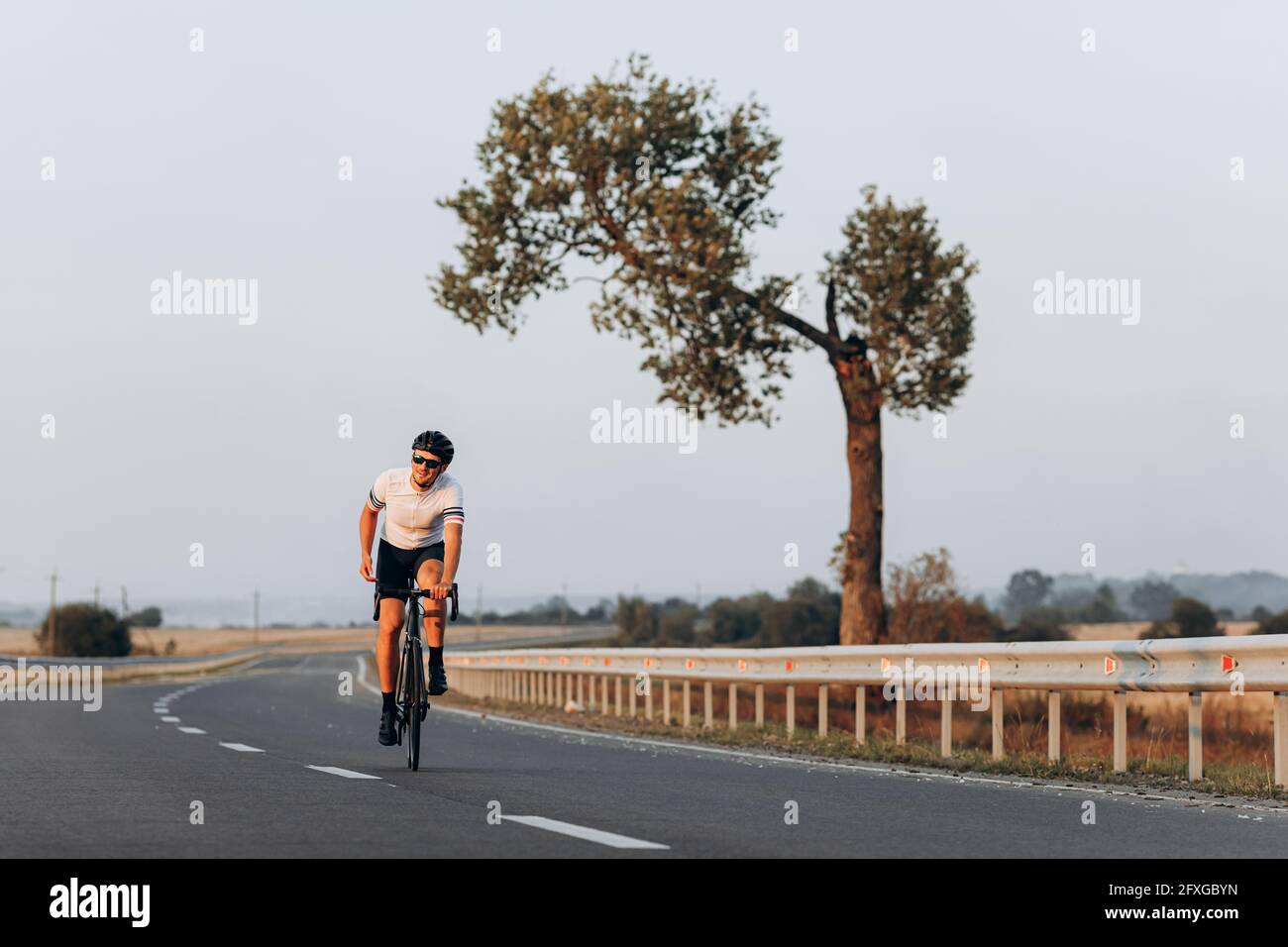 Uomo felice in casco e occhiali in bicicletta all'aperto Foto Stock