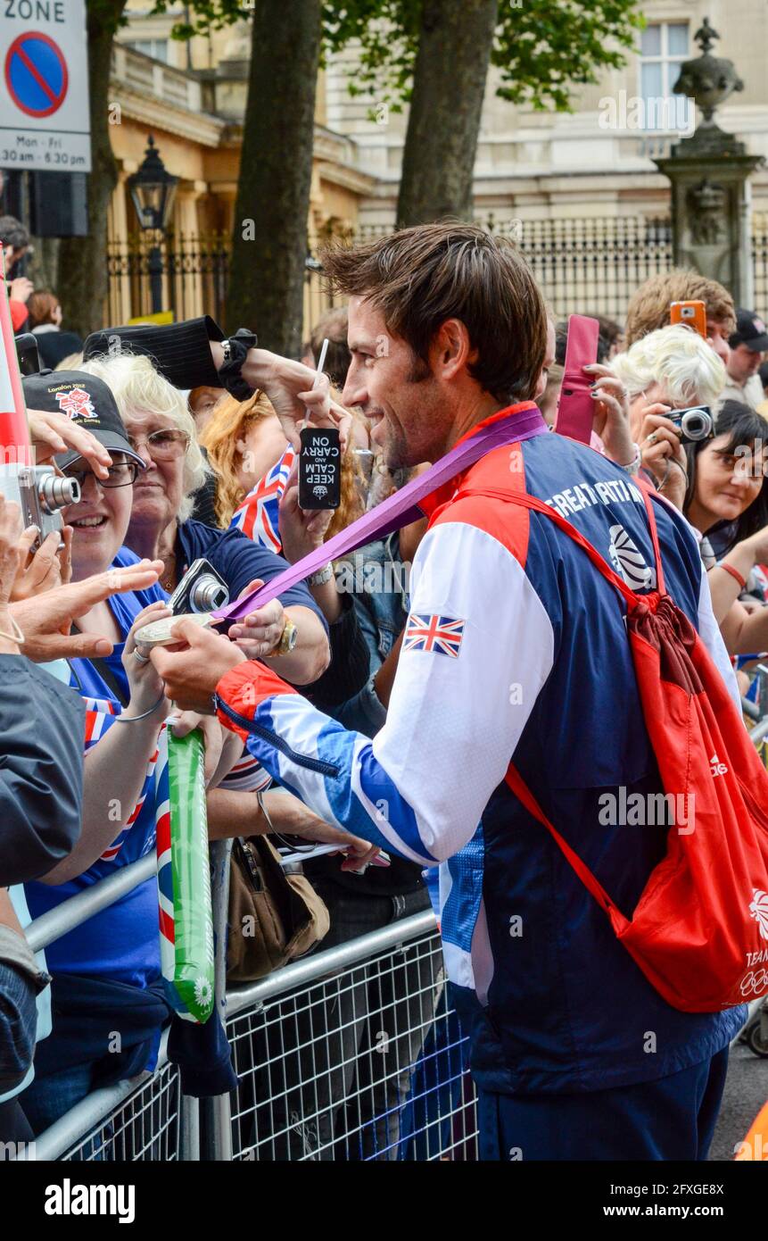 Mark Hunter mostra al pubblico la sua medaglia d'argento canottante come Team GB Olympians lasciando Buckingham Palace dopo la parata della vittoria. Olimpiadi di Londra 2012. Foto Stock