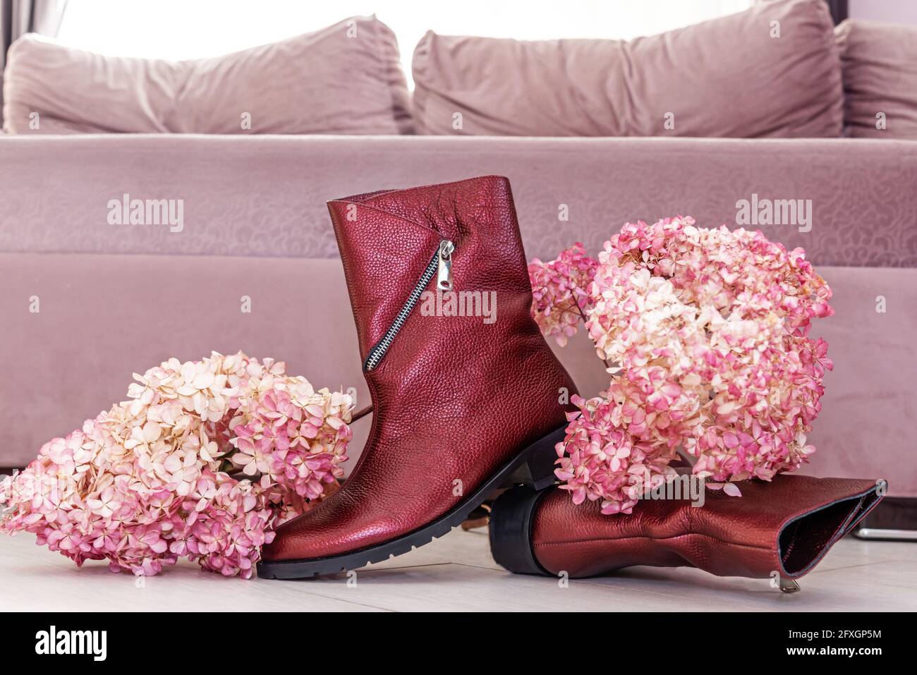Stivali eleganti con tacchi bassi e fiori lilla freschi dentro camera Foto Stock