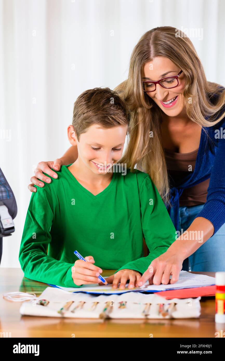 Madre aiutare figlio con compiti, la pittura di un'immagine Foto Stock