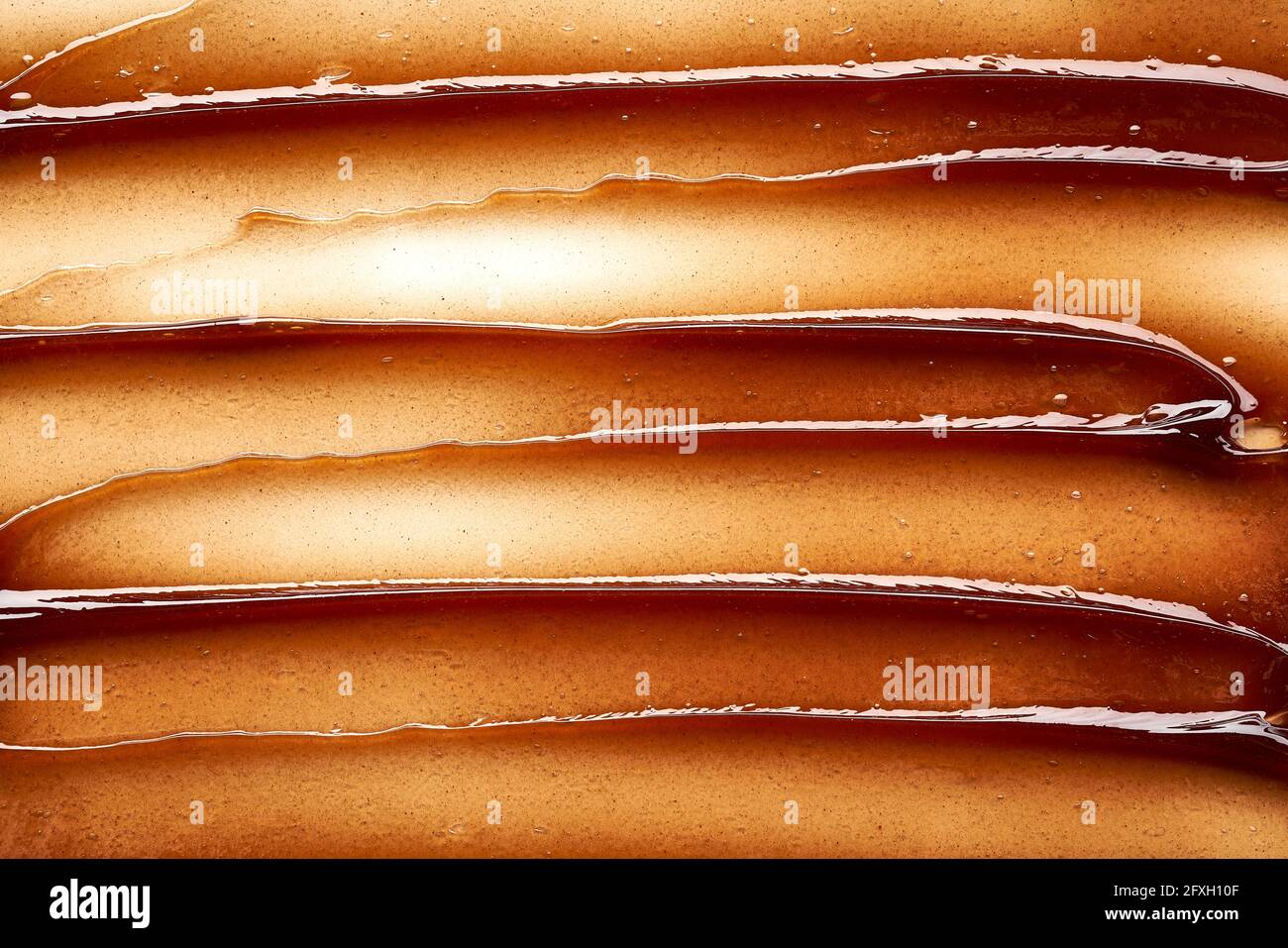 Striscio di gel color cioccolato e consistenza. Gel cosmetico o sciroppo di caramello su fondo bianco Foto Stock