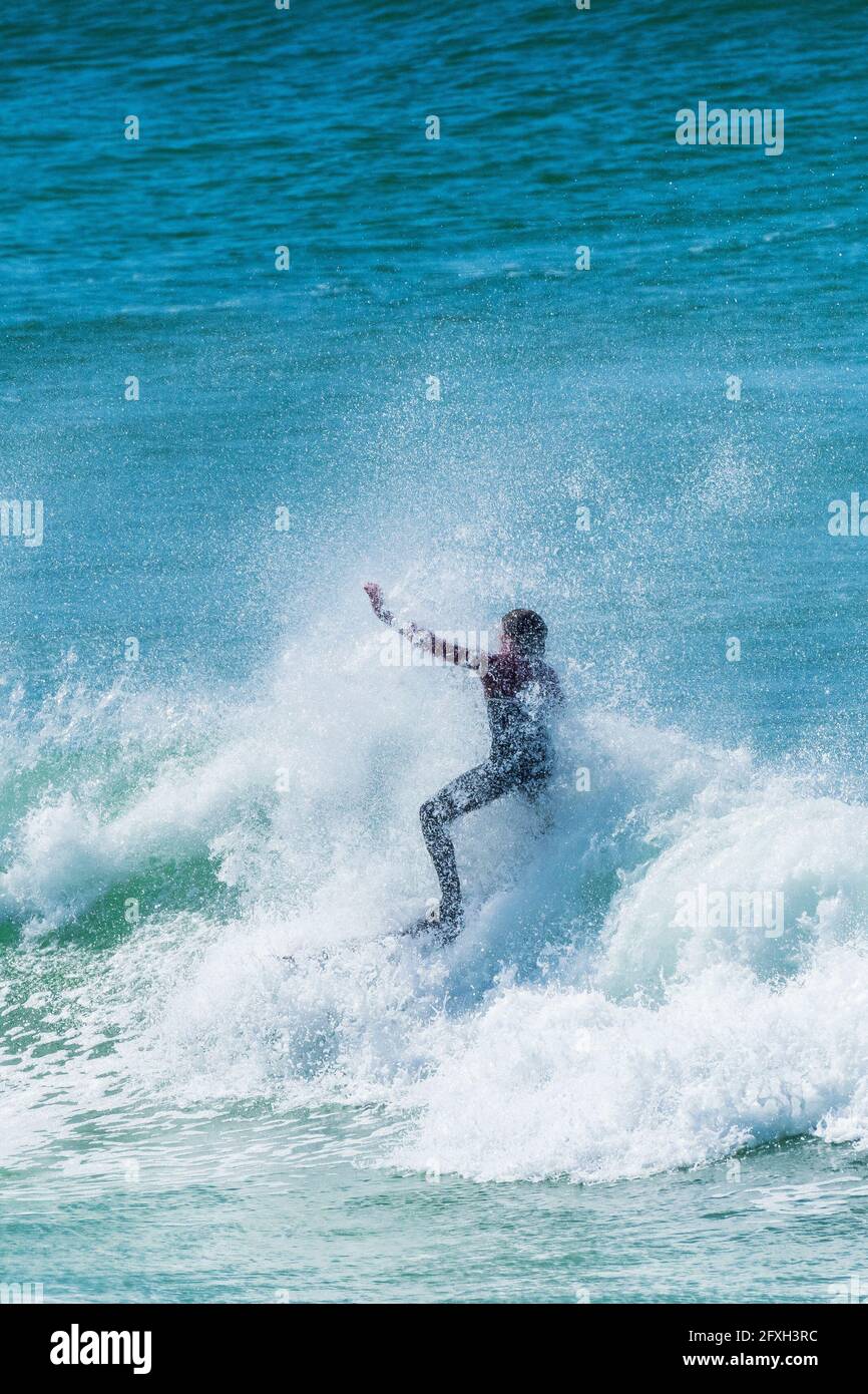La spettacolare azione di surf come surfista è travolta dallo spray mentre cavalca un'onda a Fistral a Newquay in Cornovaglia. Foto Stock