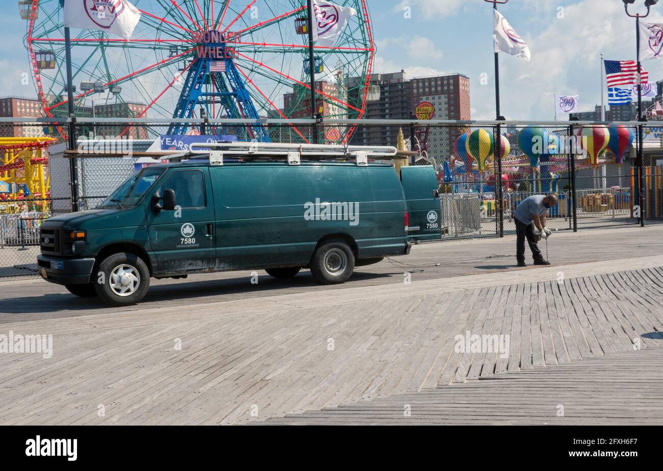 Un operaio del reparto Parchi di New York City regola e fissa le spranghe sulla passerella a Coney Island, Brooklyn, New York City. Foto Stock