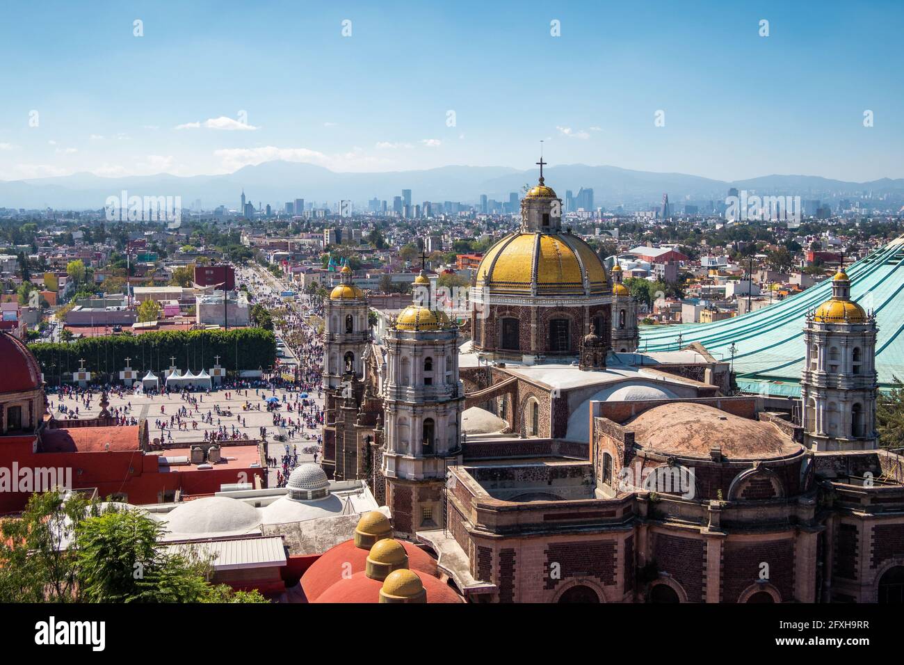 Città del Messico, Messico, storico simbolo della Basilica di nostra Signora di Guadalupe con skyline di Città del Messico in una giornata di sole. Foto Stock