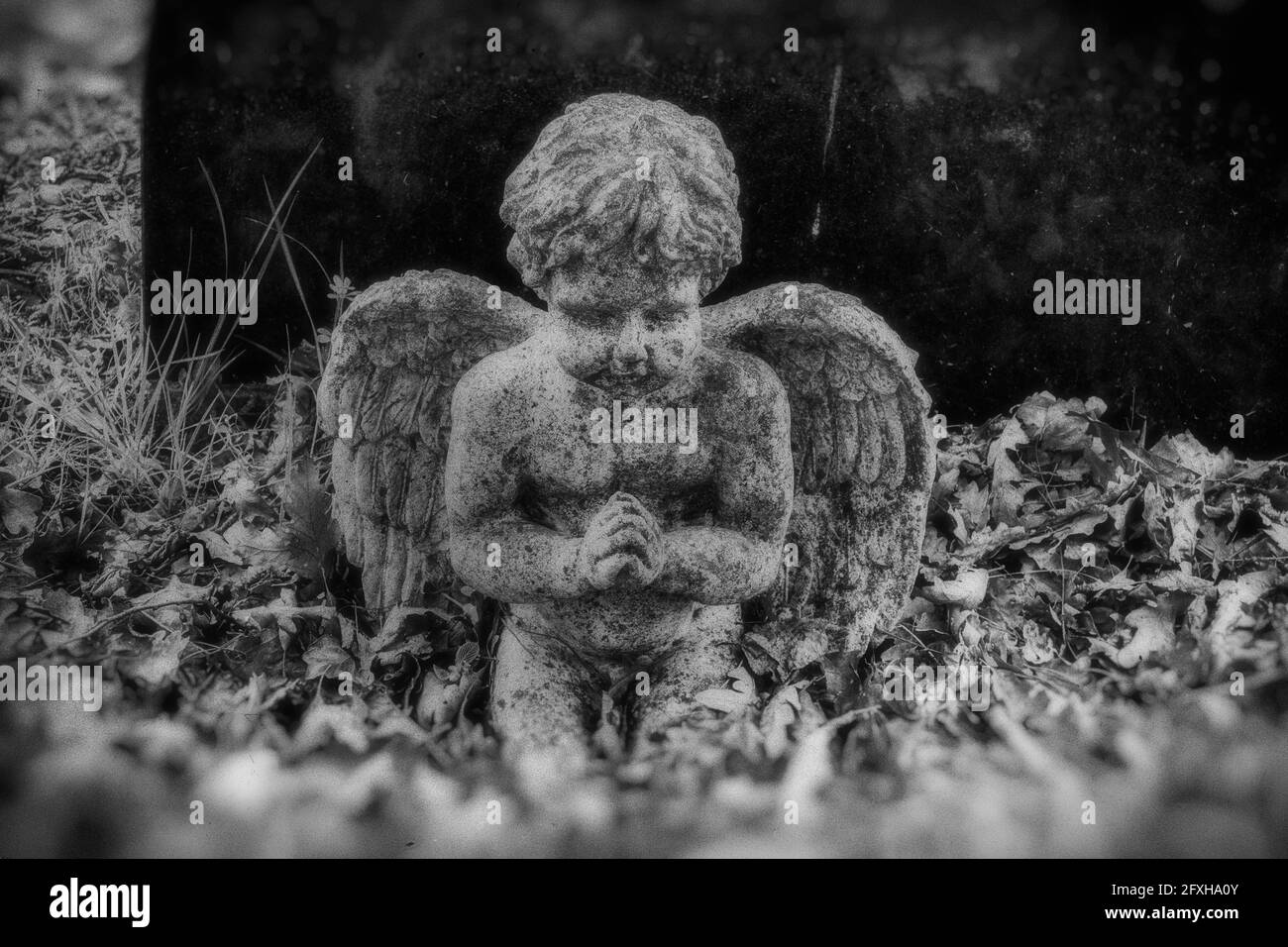 Cherubino che prega da una lapide con un effetto vintage distorto Foto Stock