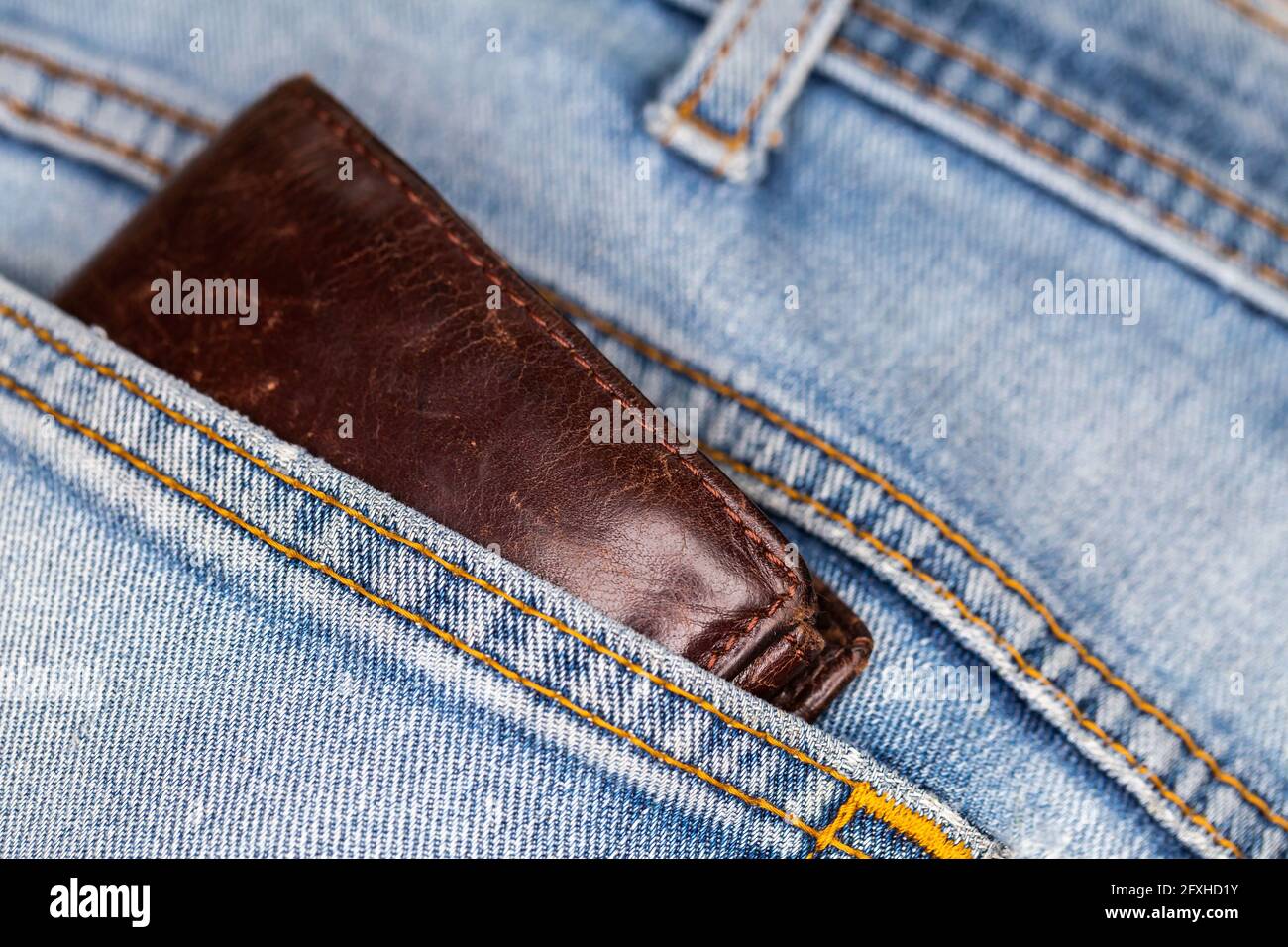 Portafoglio in pelle che fuoriesce dalla tasca posteriore dei pantaloni in  denim. Foto scattata in condizioni di luce artificiale e soffusa Foto stock  - Alamy