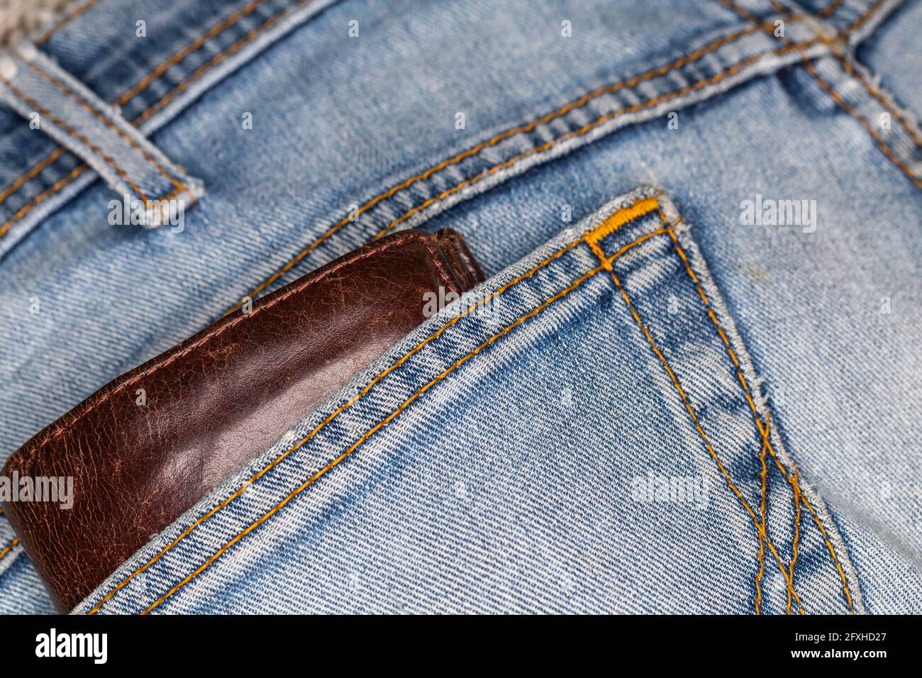 Portafoglio in pelle che fuoriesce dalla tasca posteriore dei pantaloni in  denim. Foto scattata in condizioni di luce artificiale e soffusa Foto stock  - Alamy