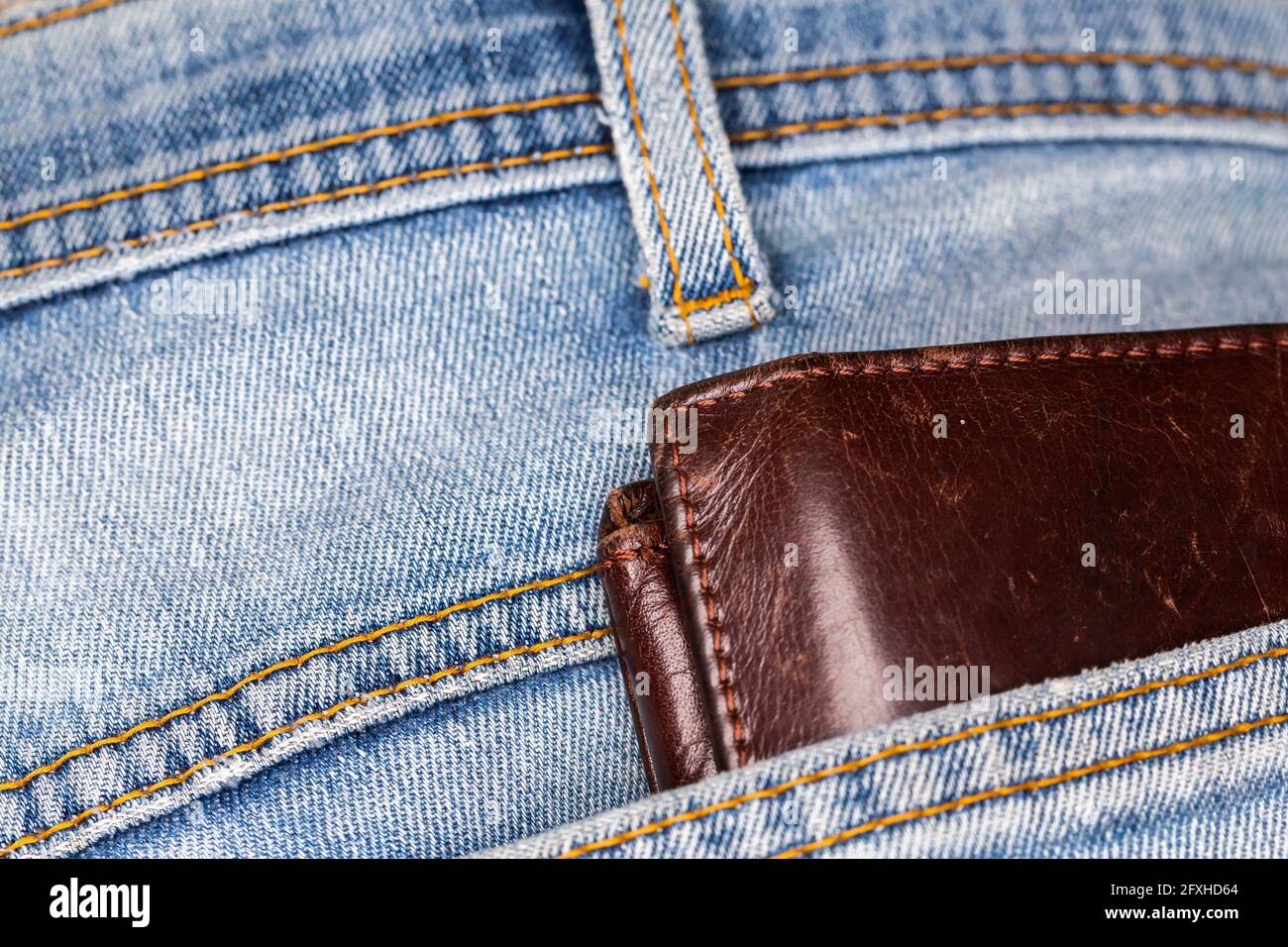 Portafoglio in pelle che fuoriesce dalla tasca posteriore dei pantaloni in  denim. Foto scattata in condizioni di luce artificiale e soffusa Foto stock  - Alamy