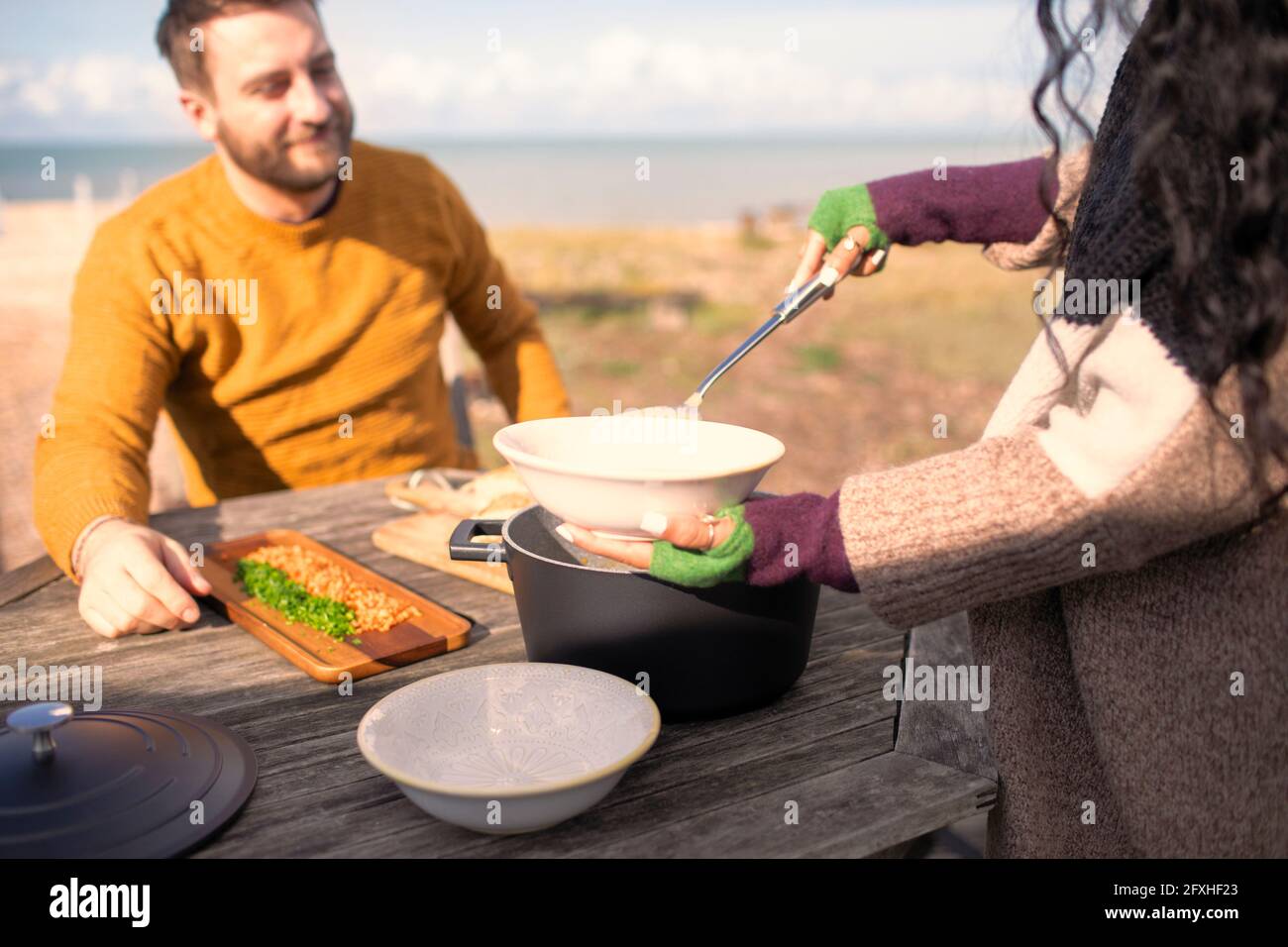 Donna che serve la zuppa. Ragazzo sul patio soleggiato della spiaggia Foto Stock