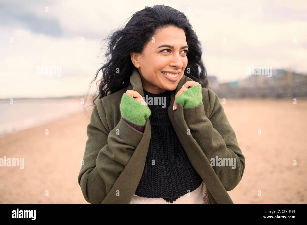 Felice bella donna in giacca invernale sulla spiaggia Foto Stock