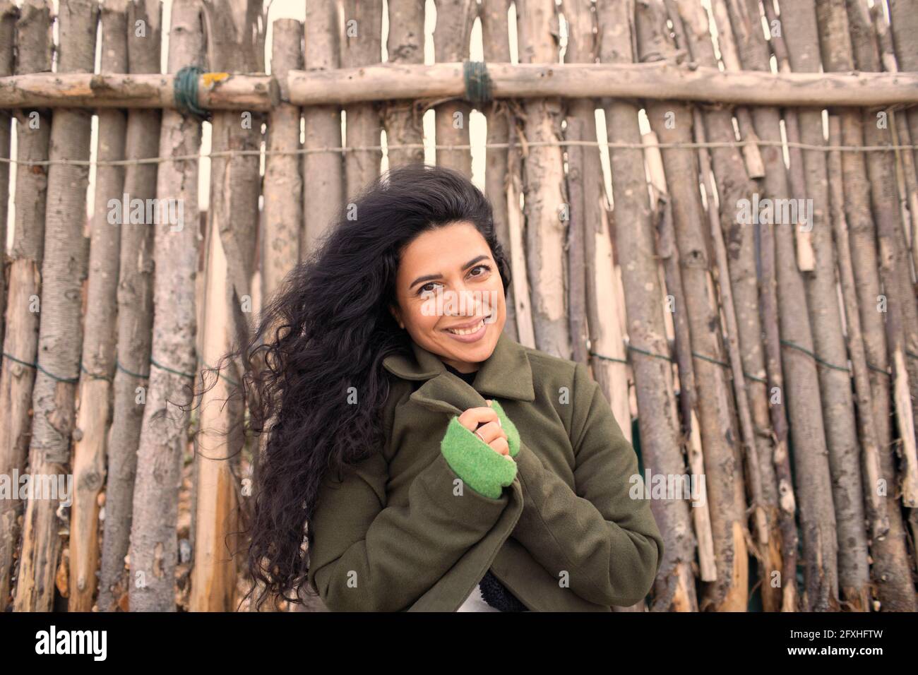 Ritratto felice bella donna in camice invernale a recinzione in legno Foto Stock