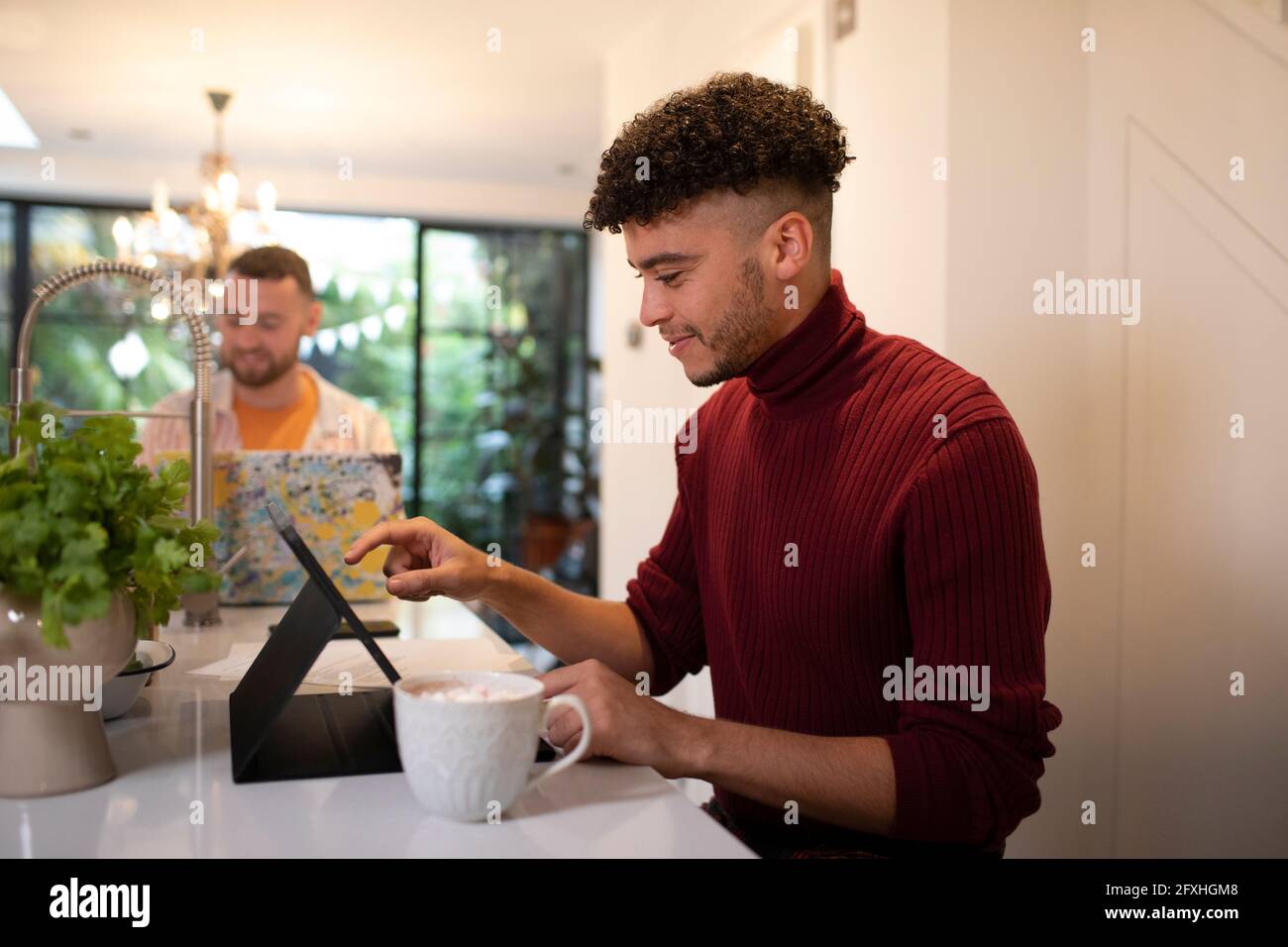 Giovane che lavora da casa al tablet digitale in cucina Foto Stock
