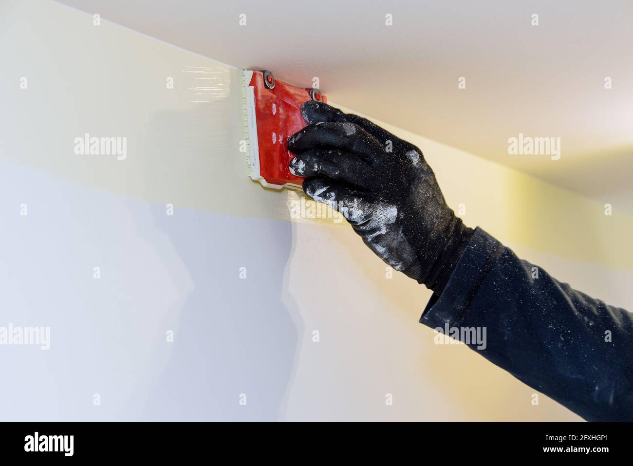 Utensile da costruzione per l'utente di un'azienda che lavora in un edger di vernice ad angolo pennellare le mani del pittore nel quadro della parete Foto Stock