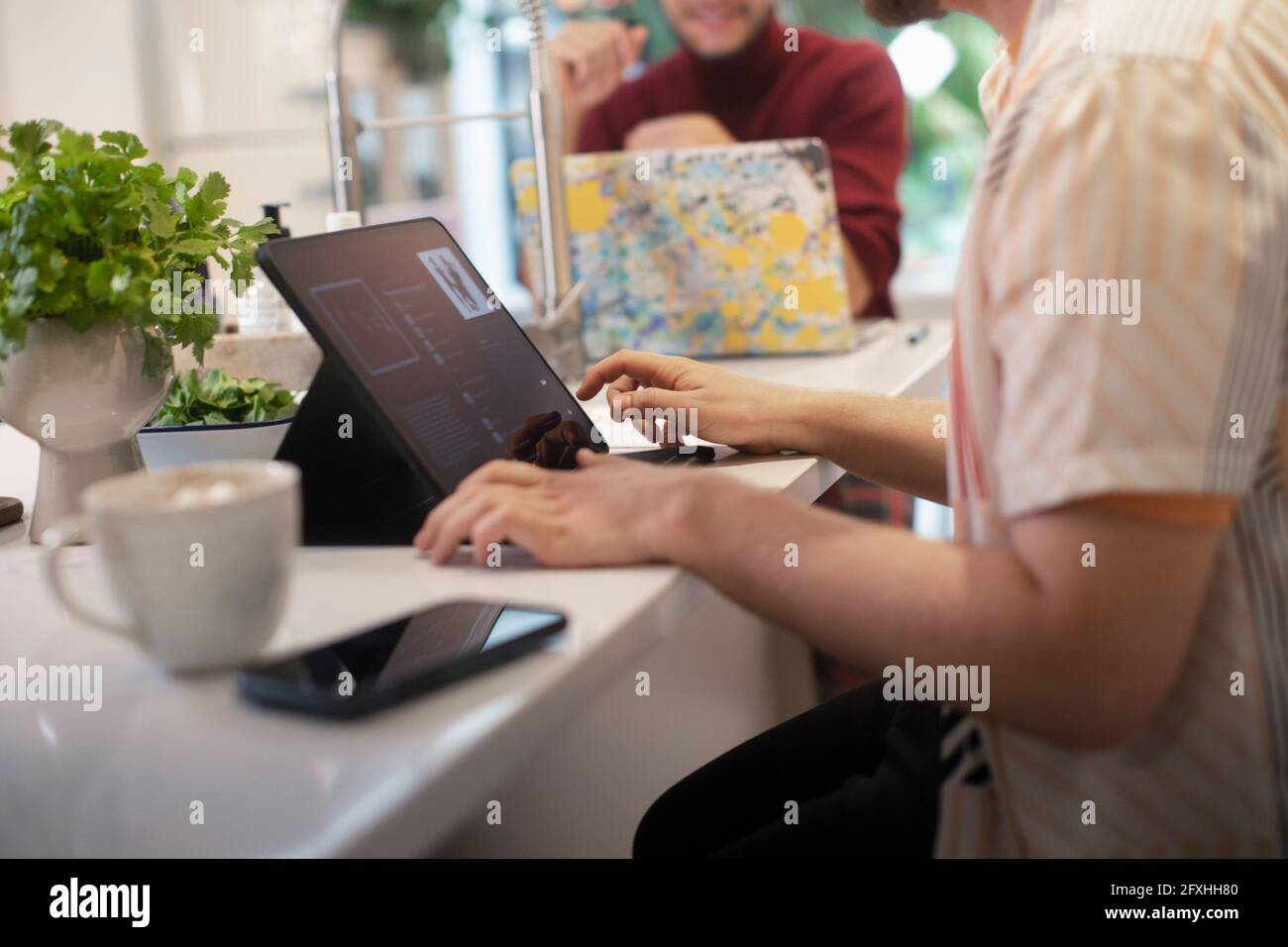 Giovane uomo che usa un tablet digitale al banco della cucina Foto Stock