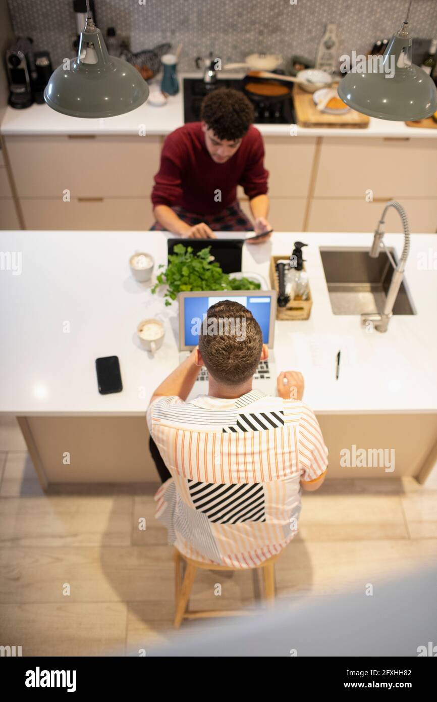 Coppia gay maschile che lavora da casa al laptop e al tablet digitale Foto Stock