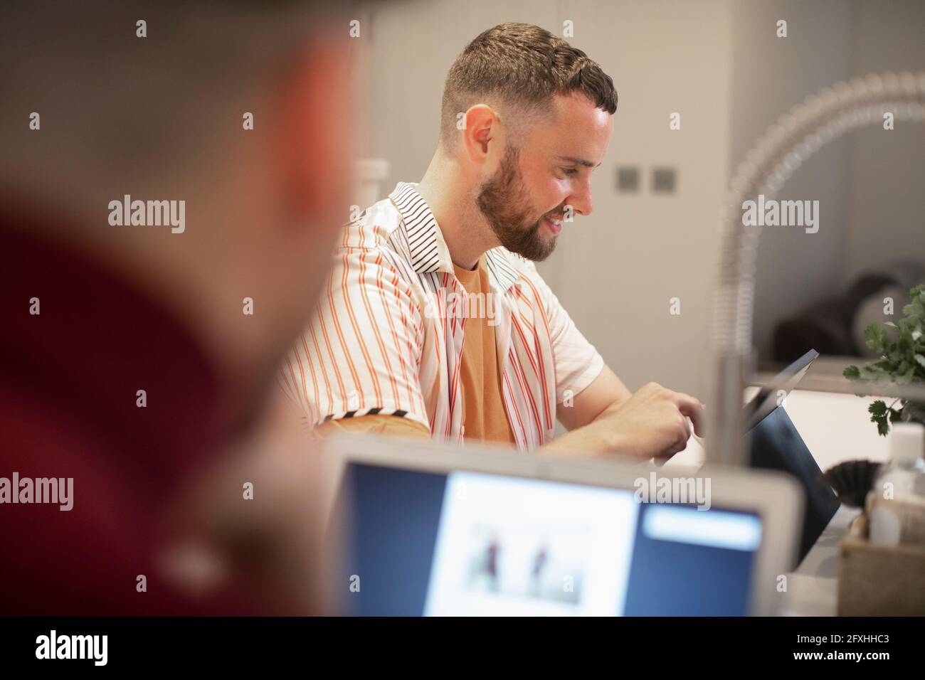 Felice giovane che lavora da casa al tablet digitale Foto Stock