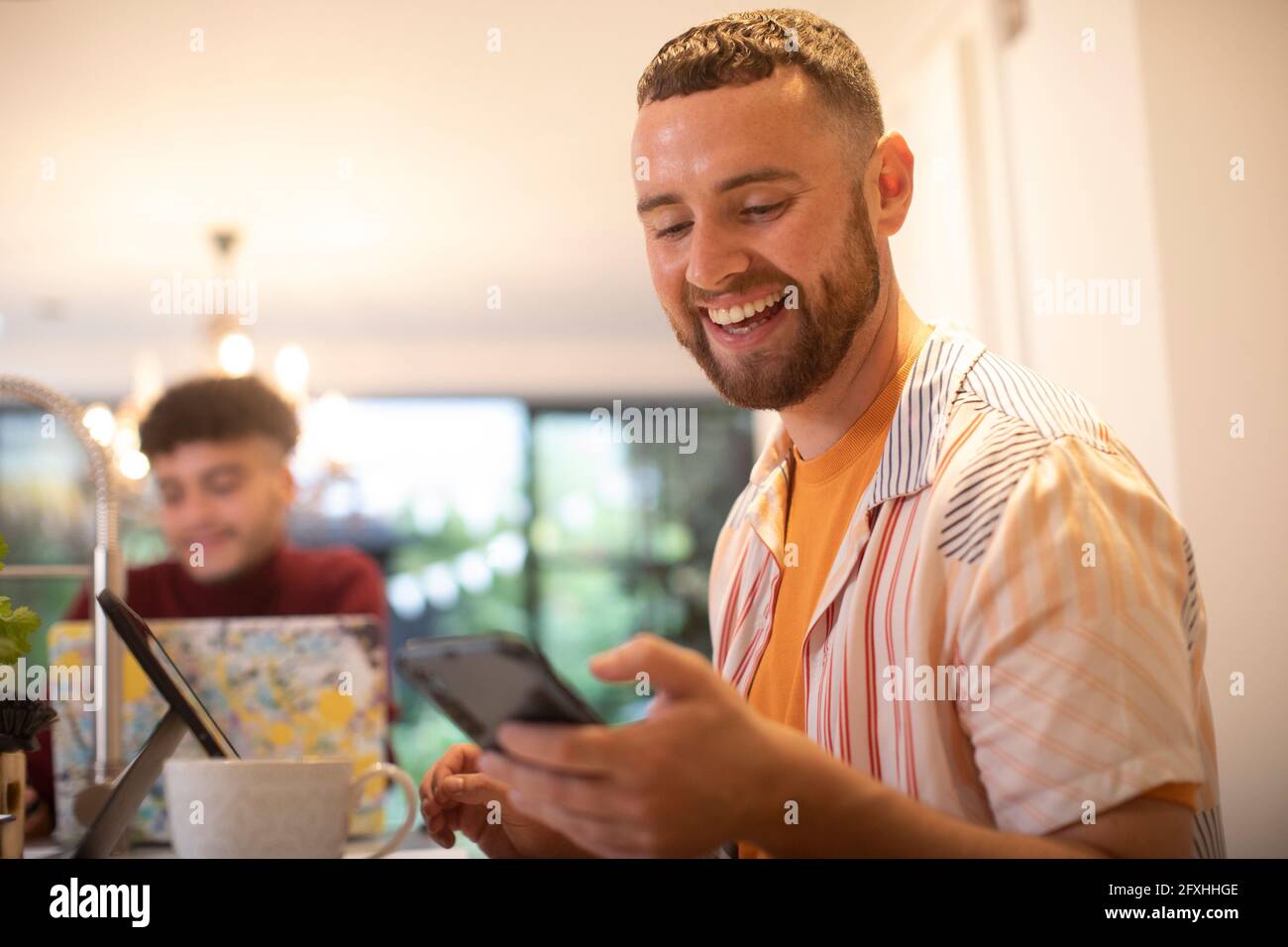 Felice giovane uomo utilizzando smart phone a casa Foto Stock