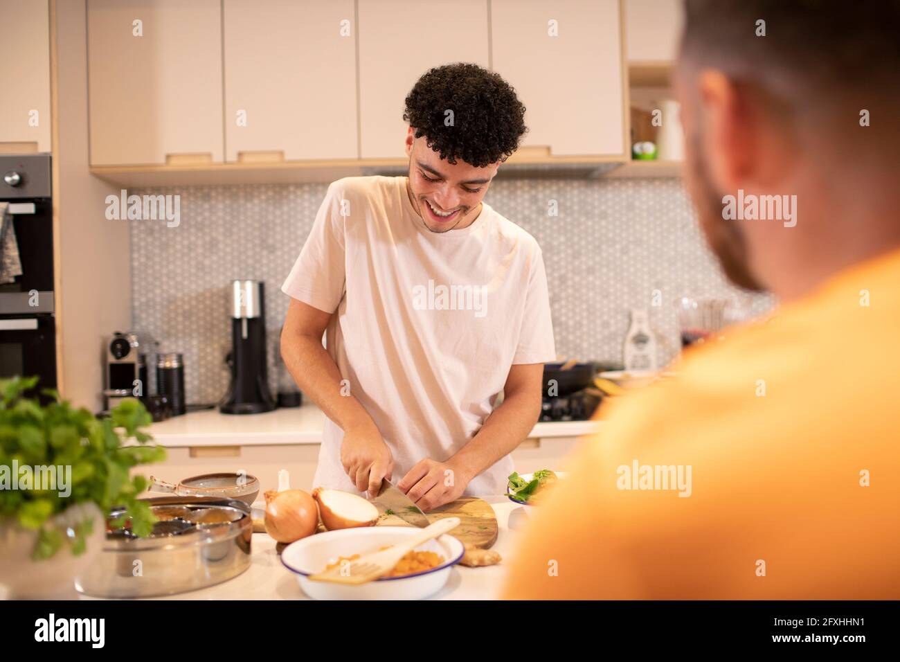 Giovane cucina tagliando cipolla in cucina Foto Stock