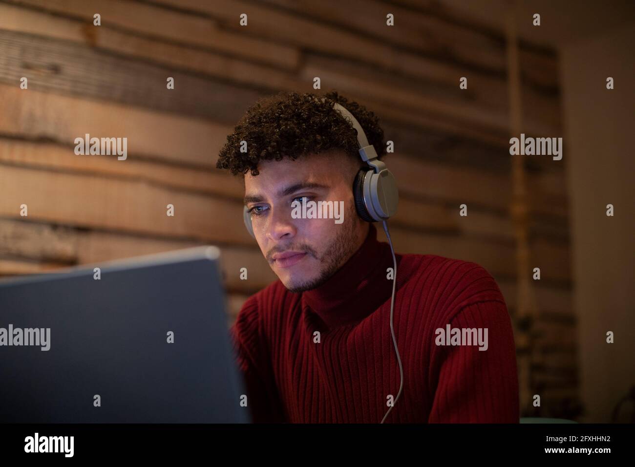 Un giovane concentrato di attenzione con le cuffie utilizzando un tablet digitale Foto Stock