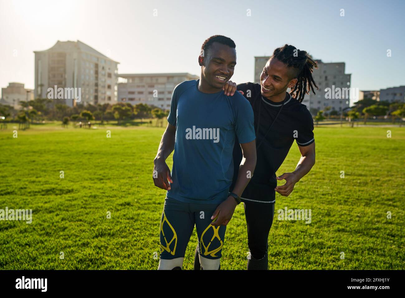 Allenatore felice e atleta amputato in campo soleggiato Foto Stock