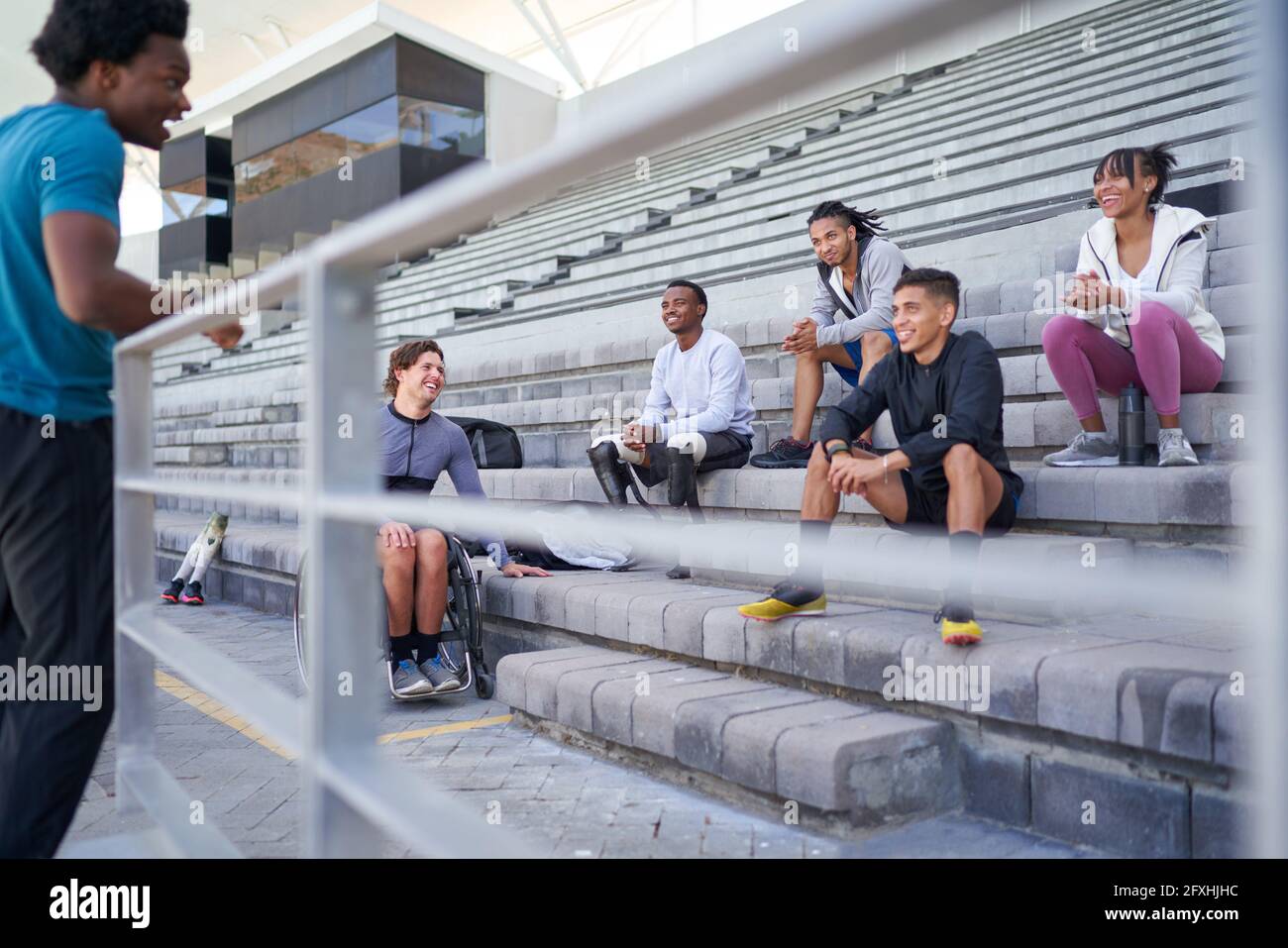 Gli amici dell'atleta che parlano nei bleachers dello stadio Foto Stock