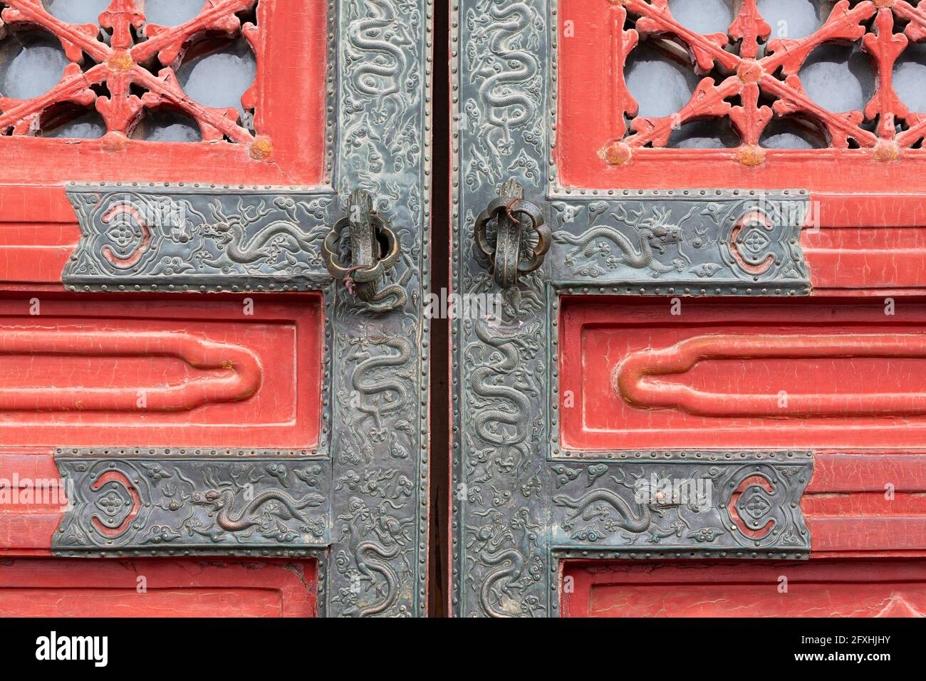 Finiture in metallo riccamente decorate con serpenti su vecchio legno rosso porta Foto Stock