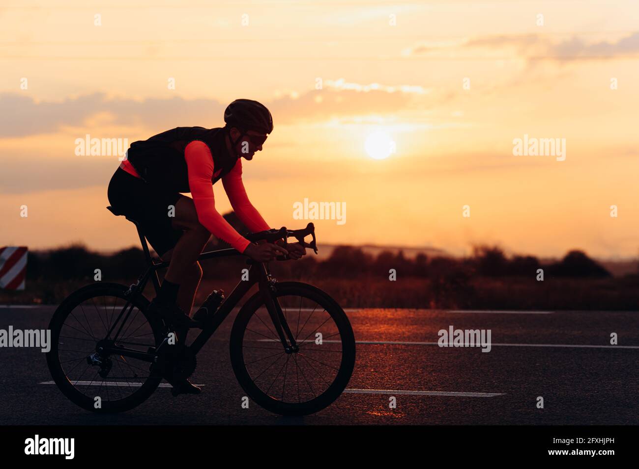 Atleta maschile in abbigliamento da ciclismo brillante che corre su strada Foto Stock