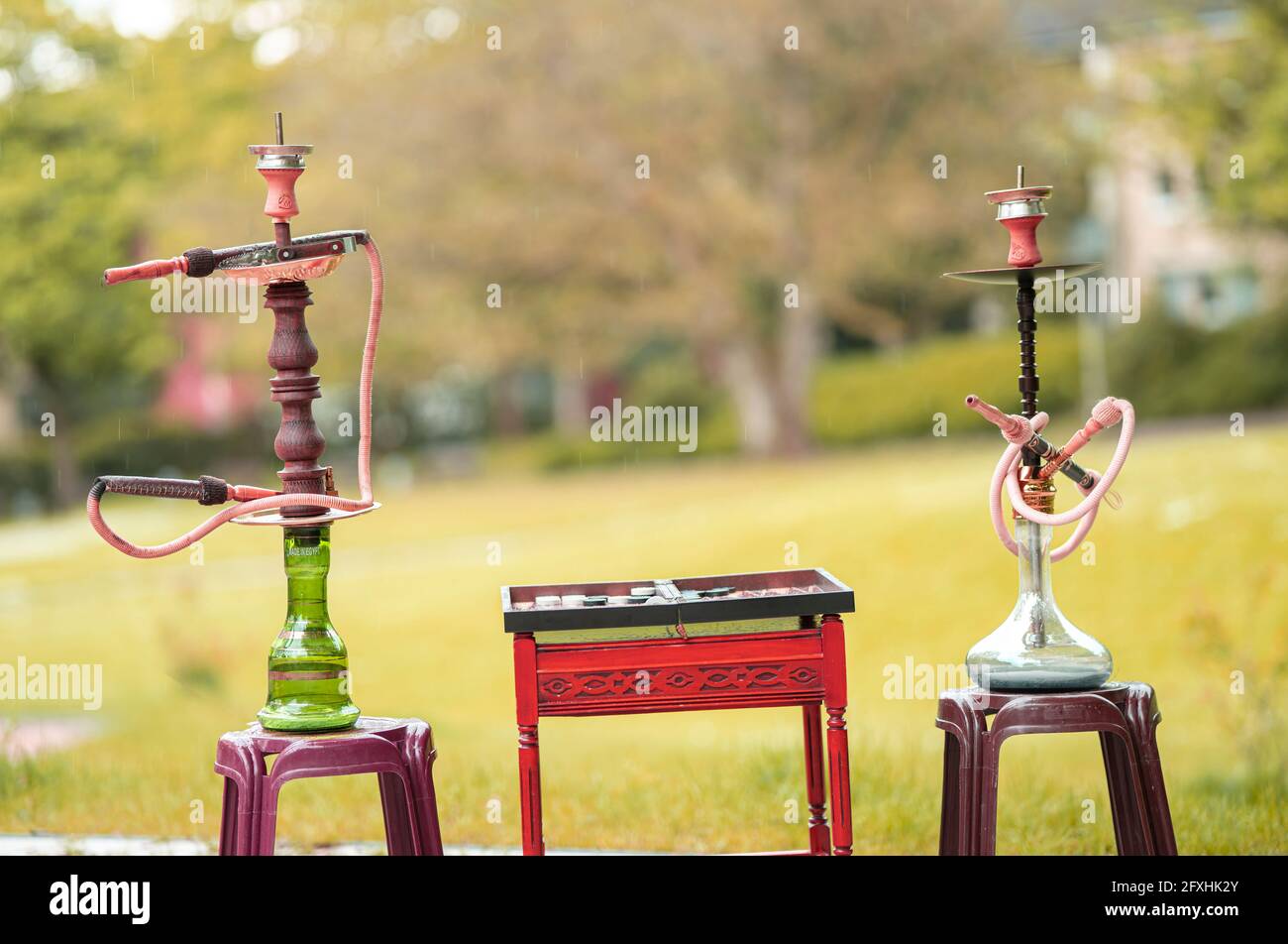 La testa di un hookah, tubo di acqua o shisha con carbone incandescente nel giardino in estate sole Germania, testa, tubo di acqua, fumo, arabesco Foto Stock
