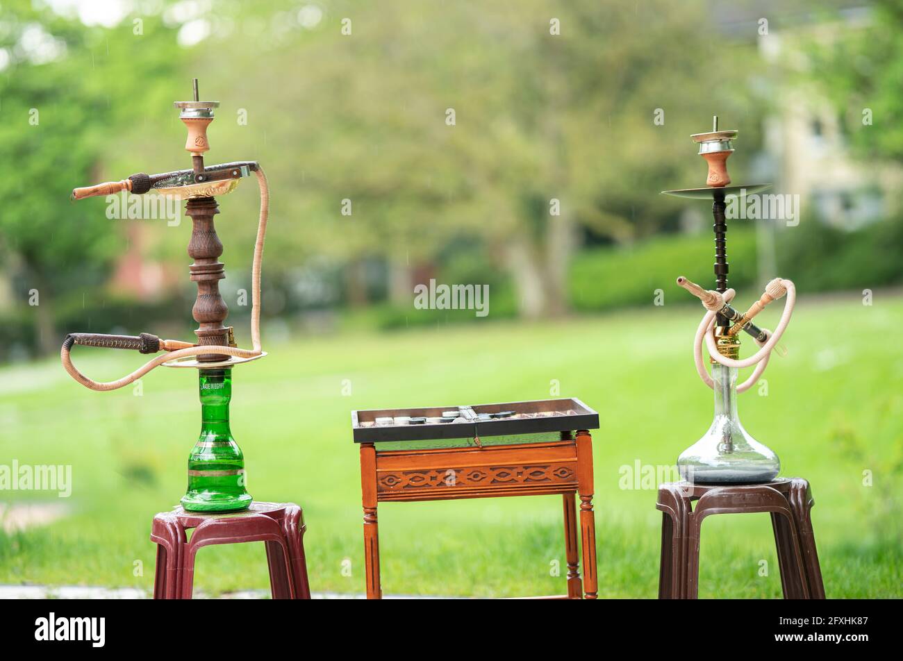 La testa di un hookah, tubo di acqua o shisha con carbone incandescente nel giardino in estate sole Germania, testa, tubo di acqua, fumo, arabesco Foto Stock