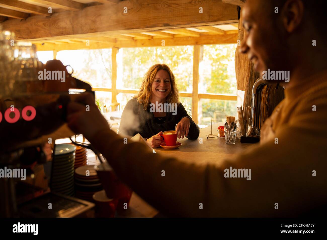 Il cliente guarda il barista preparare il caffè nella macchina espresso al bar Foto Stock