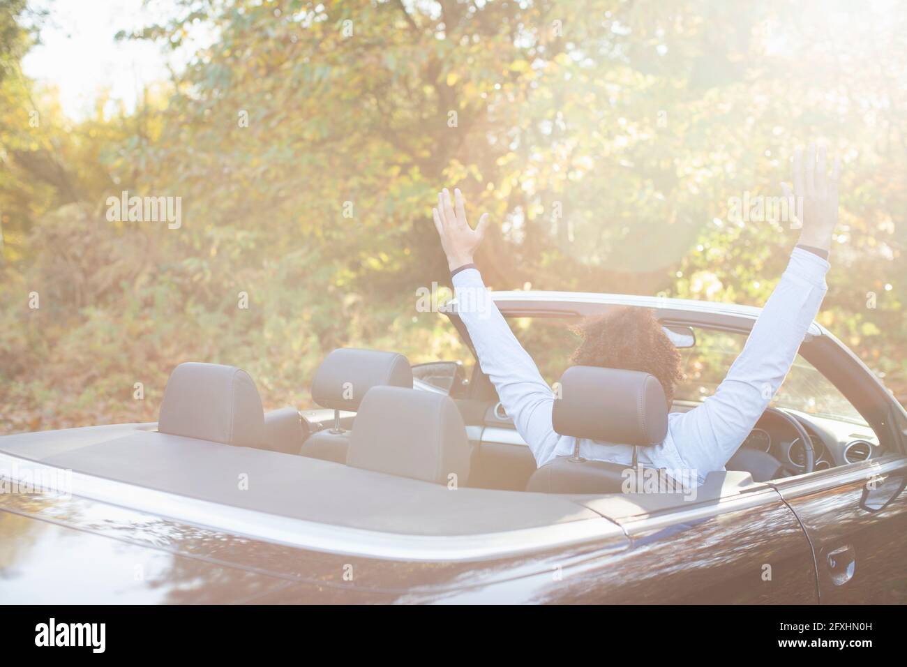 Giovane uomo spensierato in convertibile nel soleggiato parco autunnale Foto Stock