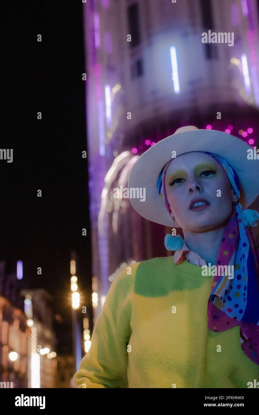 Ritratto fresco donna alla moda in fedora sotto l'edificio della città di notte Foto Stock