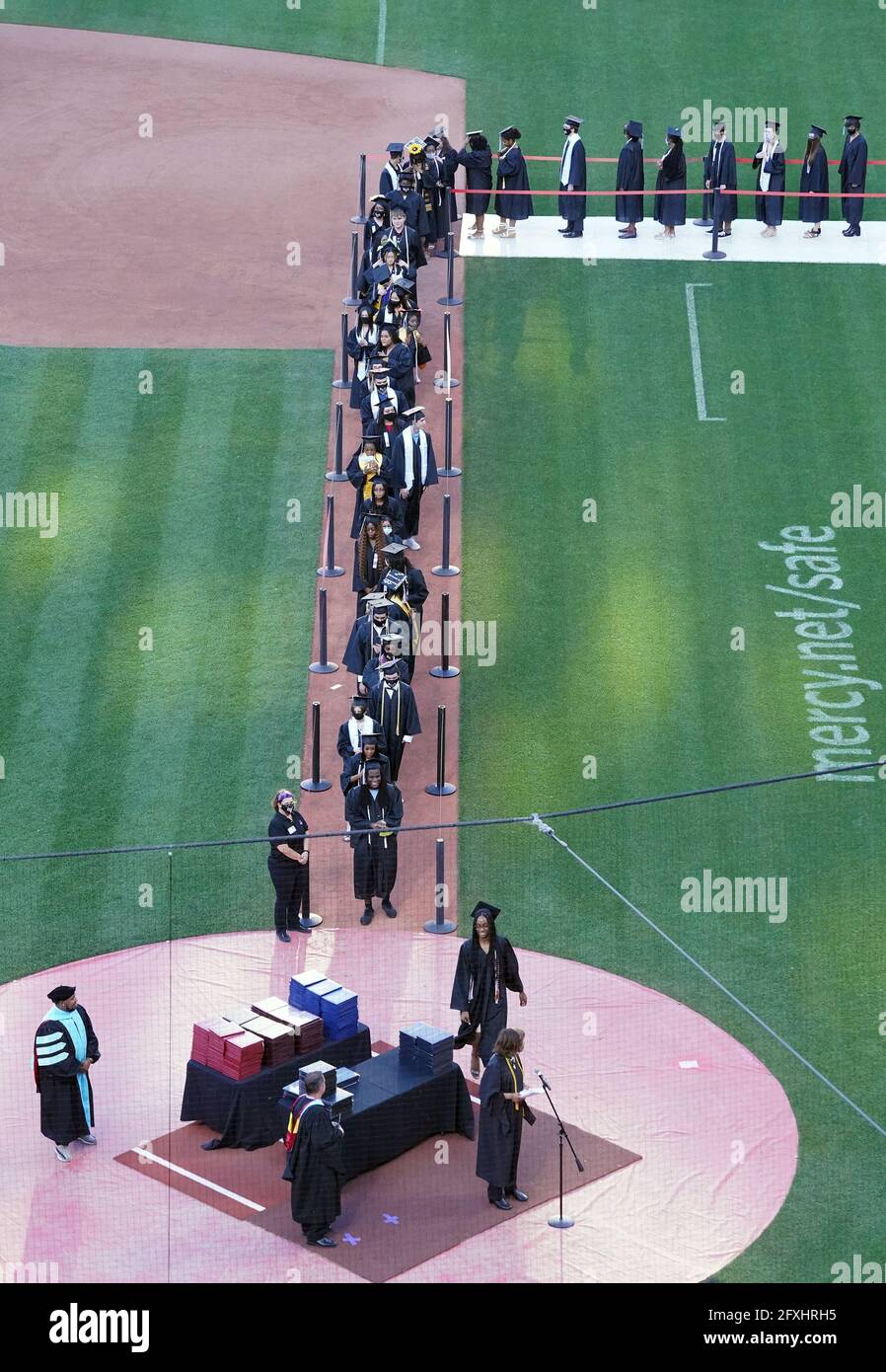 Gli anziani laureati aspettano sulla prima linea di base mentre i loro nomi sono chiamati durante la cerimonia di inizio delle scuole pubbliche di St. Louis al Busch Stadium a St. Louis mercoledì 26 maggio 2021. Foto di Bill Greenblatt/UPI Foto Stock