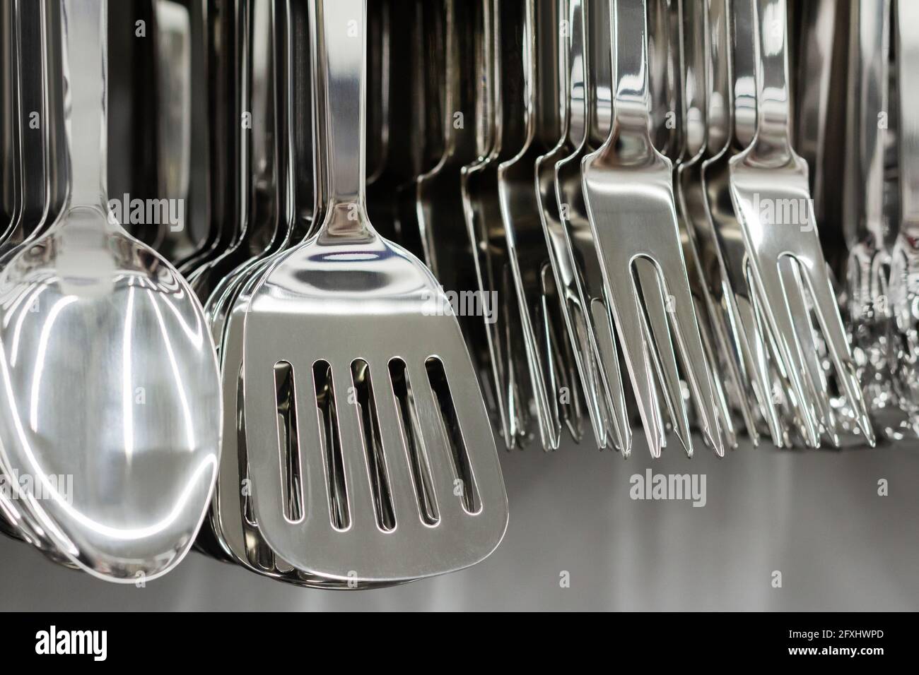 Foto di acciaio inossidabile vari utensili da cucina appesi al rack del negozio. Foto Stock