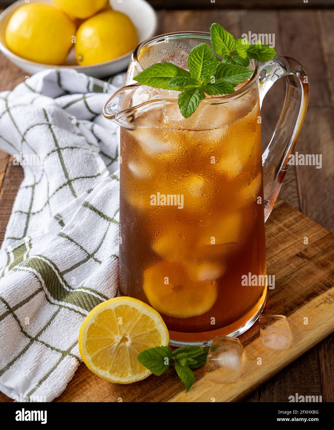 Caraffa di tè freddo con limone e menta su a. tavolo rustico in legno Foto Stock