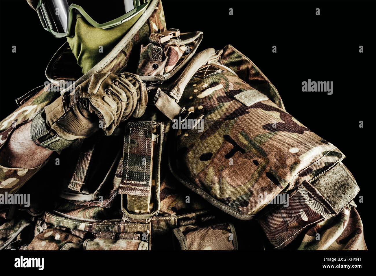 Foto di soldato in giubbotto corazzato di livello 3, guanti tattici che indossano la protezione delle spalle su sfondo nero. Foto Stock