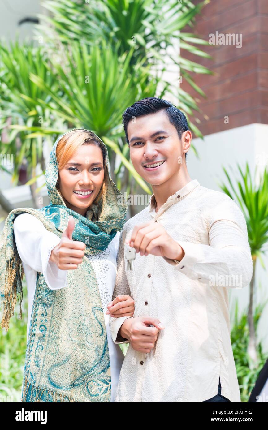 Musulmani asiatici l uomo e la donna si spostano in casa presentando latchkey o chiave Foto Stock